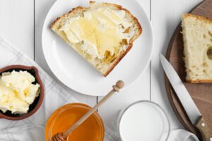 sliced milk honey bread with butter and honey. Glass of milk and jar of honey. Knife on cutting board.